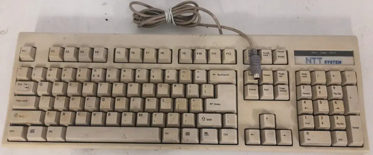 Stara klawiatura PS/2 obok nowoczesnego laptopa z adapterem USB